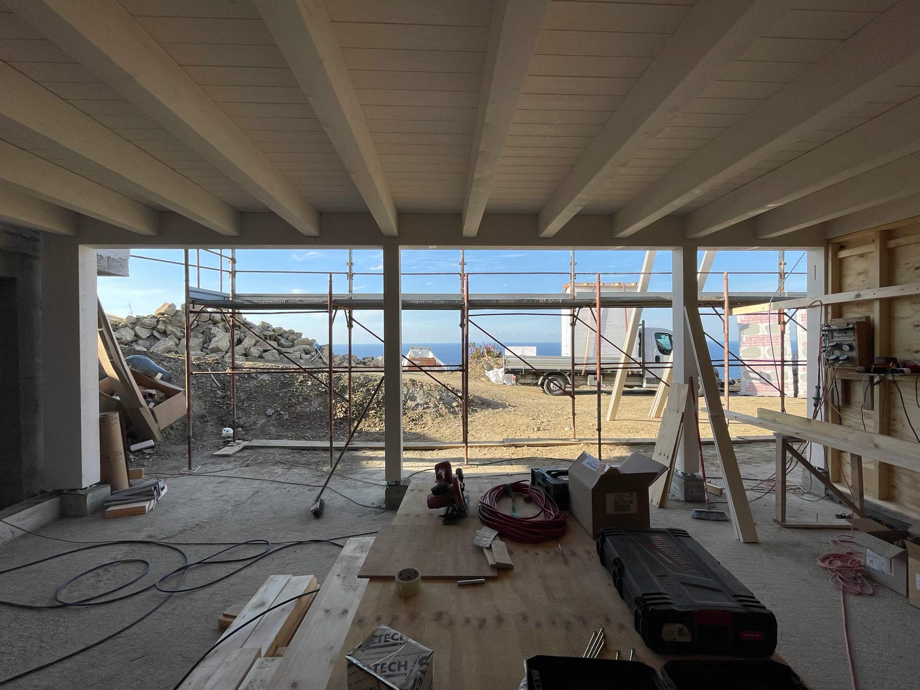 Cantiere di una casa a struttura in legno con travi sbiancate sul soffitto e vista sul mare di Sanremo