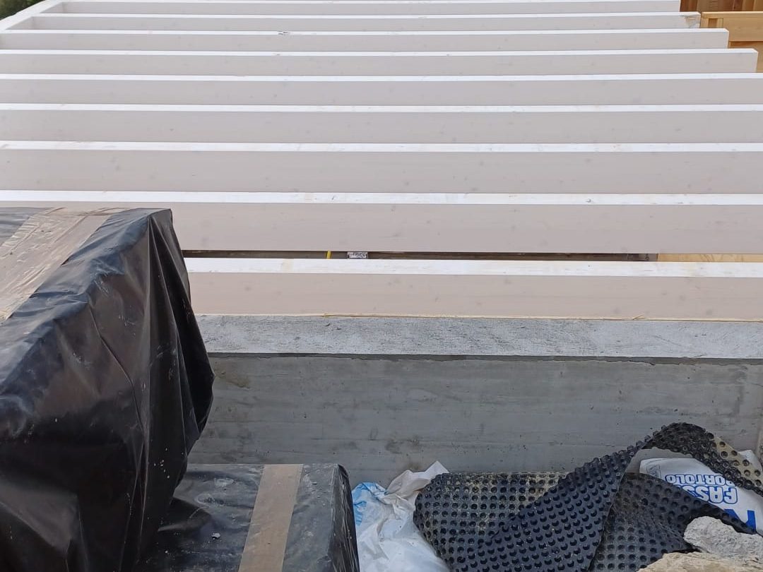 Cantiere di una casa a struttura in legno con travi sbiancate sul soffitto